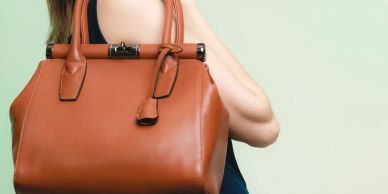 Woman holding a stylish brown leather handbag.